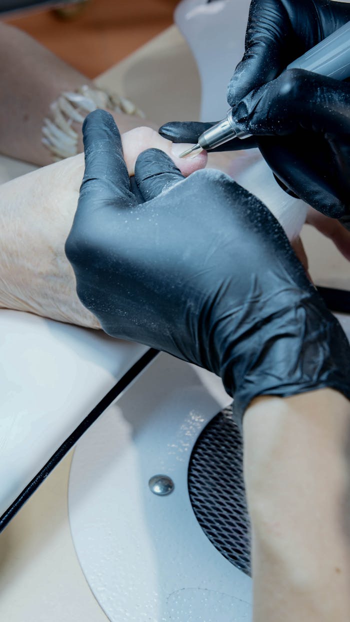 client-stories-img Close-up of a manicurist working on a client's nails using precision tools.